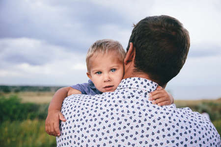 adorable toddler hugging his father and holding his neckの写真素材