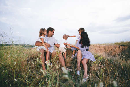 Happy dad and children having fun outdoors in a wheat field. Front viewの写真素材