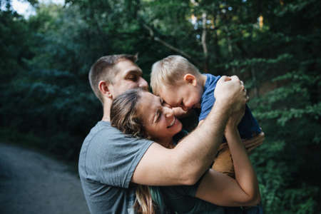 Happy joyful young family father, mother and little son having fun outdoors, playing together in...