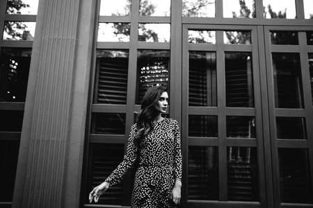 black and white photo of fashionable woman wearing a black polka dot designer dress. ideal summer...