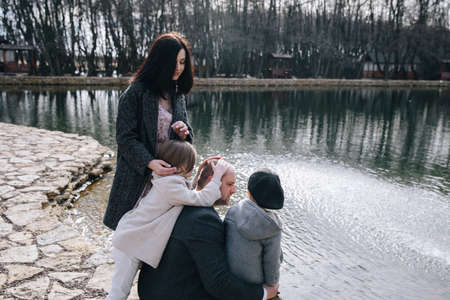 happy beautiful family having fun and walking by the lake on autumn day.