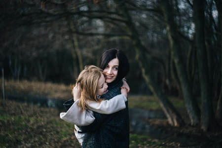 Mom and her daughter are playing and hugging outdoorの写真素材