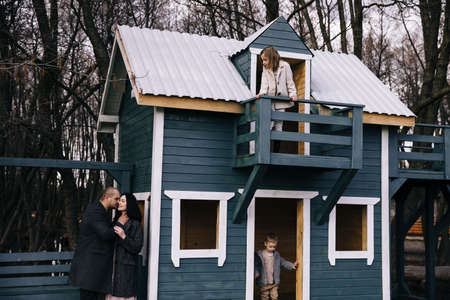 happy kids walking in late autumn garden with wooden blue house on background