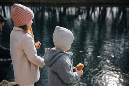 Children have feeding swans near the water. happy kids running near in the lake.の写真素材