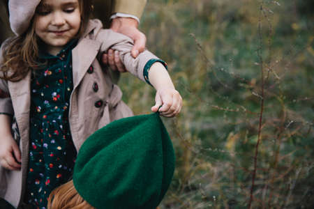 Young father, mother and little toddler daughter girl in a beret and a coat are having fun in the...