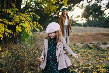 Young mother and little toddler daughter girl are walking in the autumn forest.の写真素材