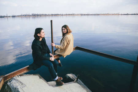 young romantic couple in coats enjoying autumn landscape on the river backgroundの写真素材