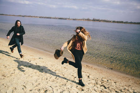 Young couple in warm coats having fun on the river bank.の写真素材