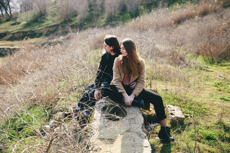 smiling couple sitting on countryside bulkhead against landscapeの写真素材