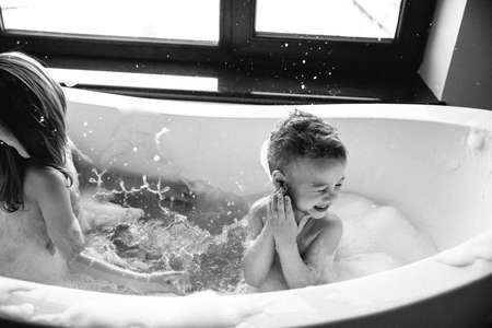 Young children take a bath. Children wash in bathroom. Brother and sister play in the bathroom during water procedures.の写真素材