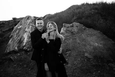 Black and white portrait of two young lovers laught by the sunset on ravine background. Couple in...
