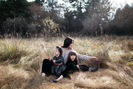 woman with daughter and son on dry grass field. wheat field. family look. cute happy familyの写真素材