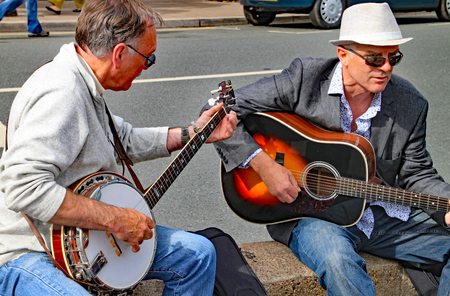 SIDMOUTH, DEVON, ENGLAND - AUGUST 8TH 2012: Two men play a guitar and a banjo on an impromptu street performance on the Esplanadeのeditorial素材