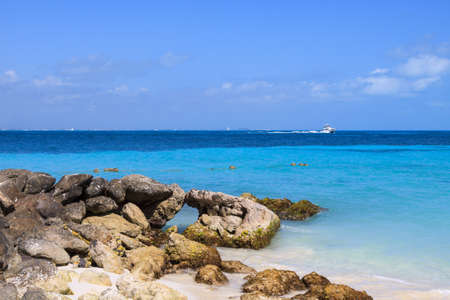 A view of the Caribbean with rocks, layers of blue water and white clouds.
