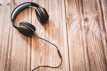 A pair of headphones resting on a rustic wooden background with copy spaceの写真素材