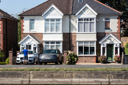 09/02/2019 Emsworth, Hampshire, UK A man washing his car on his drive way using a hose in front of two typical English housesのeditorial素材