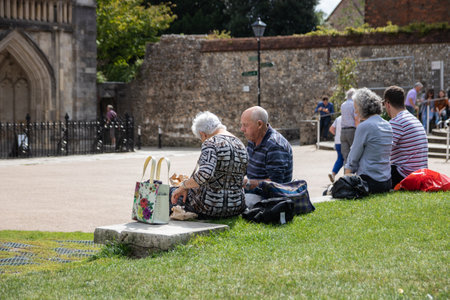 09/02/2019 Winchester, Hampshire, UK an elderly couple sat on a wall in the park enjoying lunch in the sunshineのeditorial素材