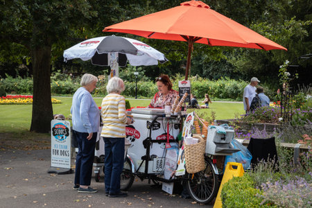 09/02/2019 Winchester, Hampshire, UK Two elderly women buying an Ice cream from a traditional ice cream sellers bicycle in an english park during summersのeditorial素材