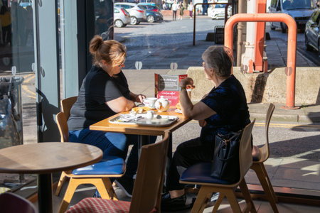 09/14/2019 Portsmouth, Hampshire, UK a middle aged woman and her elderly mother talking whilst having a coffee in a coffee shopのeditorial素材