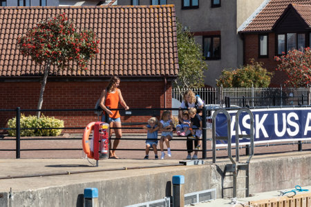 09/14/2019 Portsmouth, Hampshire, UK A family looking over railings at a lock watching boats enter a harbourのeditorial素材