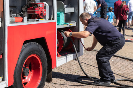 09/14/2019 Portsmouth, Hampshire, UK A British firefighter pulling a hose from a fire engine