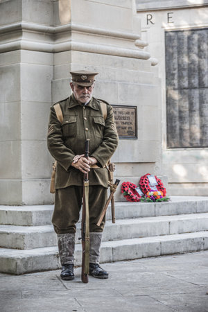 09/14/2019 Portsmouth, Hampshire, UK A man in World war one soldiers uniform standing next to a British war memorial with red poppy wreaths laid on itのeditorial素材