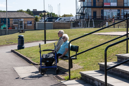 09/14/2019 Portsmouth, Hampshire, UK An elderly couple sat on a park bench in the sunのeditorial素材