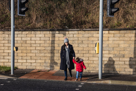 09/14/2019 Portsmouth, Hampshire, UK a mother crossing the road at traffic lights with her young childのeditorial素材