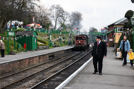 09/14/2019 Ropley, Hampshire, UK a railway guard in uniform at a training station platform with a train passingのeditorial素材
