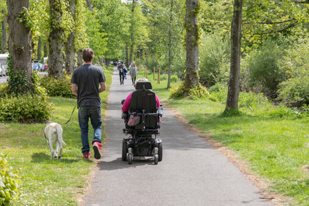 08/10/2019 Arundel, West Sussex, UK a woman in an electric scooter with her carer walking next to her with a support dogのeditorial素材
