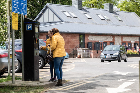 09/14/2019 Portsmouth, Hampshire, UK two women using a pay and display parking machine or meter in a car parkのeditorial素材