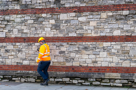 11/05/2019 Portsmouth, Hampshire, UK a builder or construction worker wearing high visibility clothing and a hard hat walkingのeditorial素材
