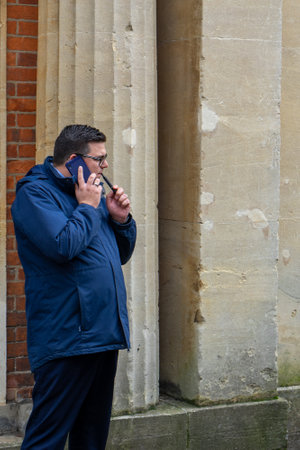 11/06/2019 Winchester, Hampshire, UK a man stand alone in the street vaping and talking on his mobile phone or cell phoneのeditorial素材