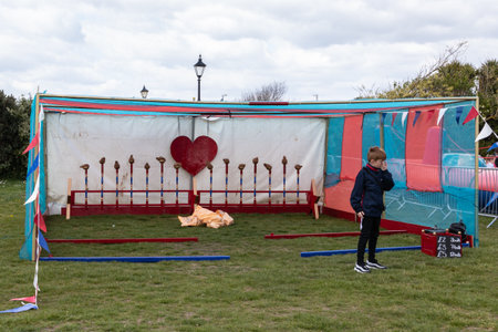 09/14/2019 Portsmouth, Hampshire, UK a boy standing in front of a coconut shy stand at a fairのeditorial素材