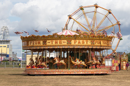 09/14/2019 Portsmouth, Hampshire, UK A traditional carousel at the fairground with a big wheel behindのeditorial素材