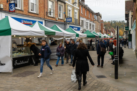 11/06/2019 Winchester, Hampshire, UK Shopper walking through a high street next to market stallsのeditorial素材