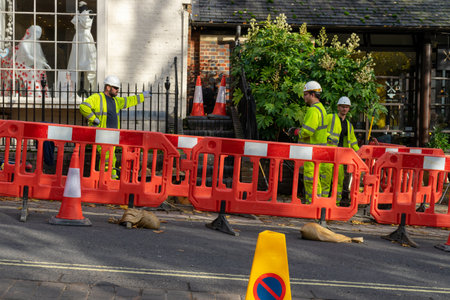 11/06/2019 Winchester, Hampshire, UK Three Builders in high visibility clothing behind a barrier in the road standing around talkingのeditorial素材