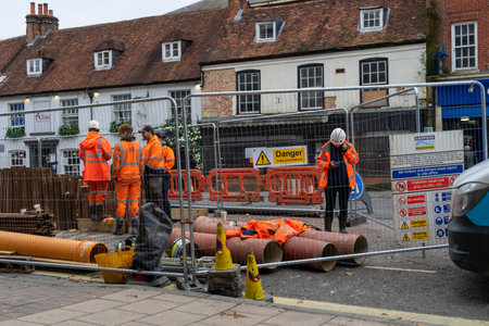 11/06/2019 Winchester, Hampshire, UK construction worker or builder working in high visibility clothing while digging up pipes in a roadのeditorial素材