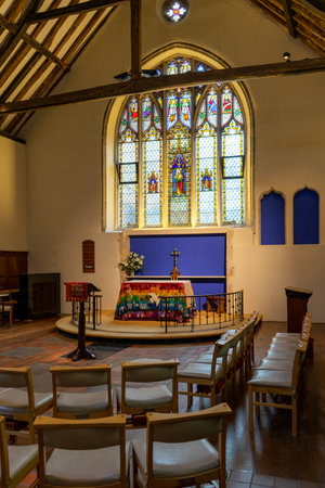 11/06/2019 Winchester, Hampshire, UK The altar of an anglican church with a stained glass window behind surrounded by chairsのeditorial素材