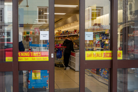 02/05/2020 Chichester, West sussex, UK Looking through supermarket doors at a woman buying goods from a frozen food aisleのeditorial素材
