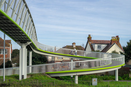 02/05/2020 Chichester, West sussex, UK A young woman pushing a pram or pushchair over a modern metal spiral bridgeのeditorial素材