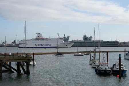 01/29/2020 Gosport, Hampshire, UK A Brittany ferries passenger ferry passing HMS Price of Wales aircraft carrier in Portsmouth Harbour, UKのeditorial素材