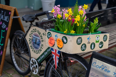 02/05/2020 Chichester, West sussex, UK spring flowers in the basket of an old bicycle outside a newsagentのeditorial素材