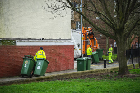 02/18/2020 Portsmouth, Hampshire, UK A group of bin men pulling recycling bins to load on a rubbish truck or garbage truckのeditorial素材
