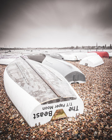 07/01/2020 Portsmouth, Hampshire, UK upturned wooded fishing boats on a pebble beach on a wet and...