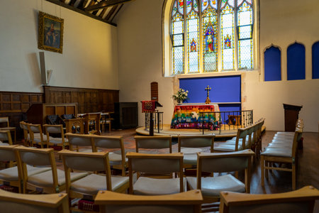 11/06/2019 Winchester, Hampshire, UK The altar of an anglican church with a stained glass window behind surrounded by chairsのeditorial素材