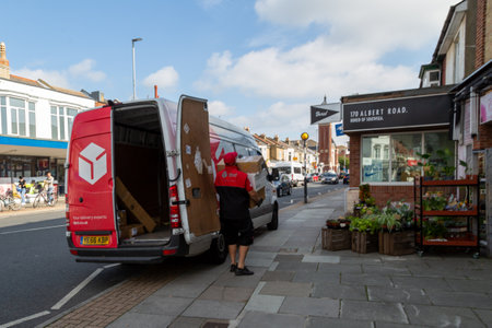 09/29/2020 Portsmouth, Hampshire, UK A DPD parcel delivery driver carrying parcels from his van doors into a shopのeditorial素材