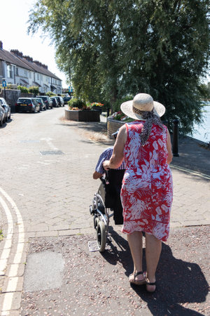 A middle aged woman pushing an elderly man in a wheelchairの写真素材