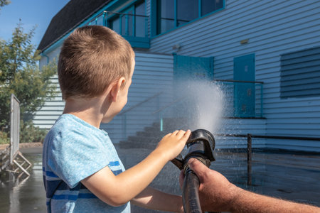 A small boy spraying water from a fire hoseの写真素材