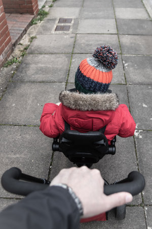 a small boy being pushed along on a push along tricycle